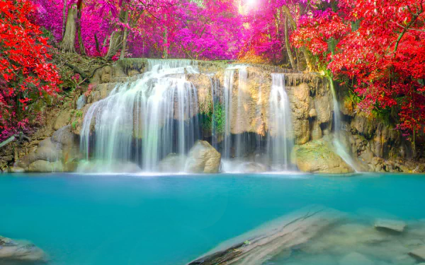A vibrant waterfall cascades into turquoise water, surrounded by lush trees adorned with vivid pink and red leaves, capturing the essence of fall in nature. 