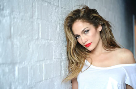 Brunette celebrity Jennifer Lopez poses against a white wall, showcasing her signature red lipstick and stunning brown eyes in this HD desktop wallpaper.