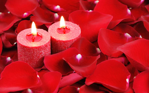 A 4K Ultra HD desktop wallpaper featuring two glowing red candles surrounded by vibrant red petals in a close-up photography composition.