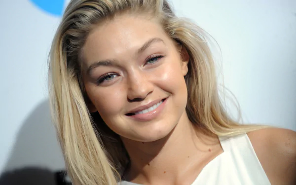 Image of a smiling blonde American model with green eyes, identified as Gigi Hadid, featured on an HD desktop wallpaper and background.