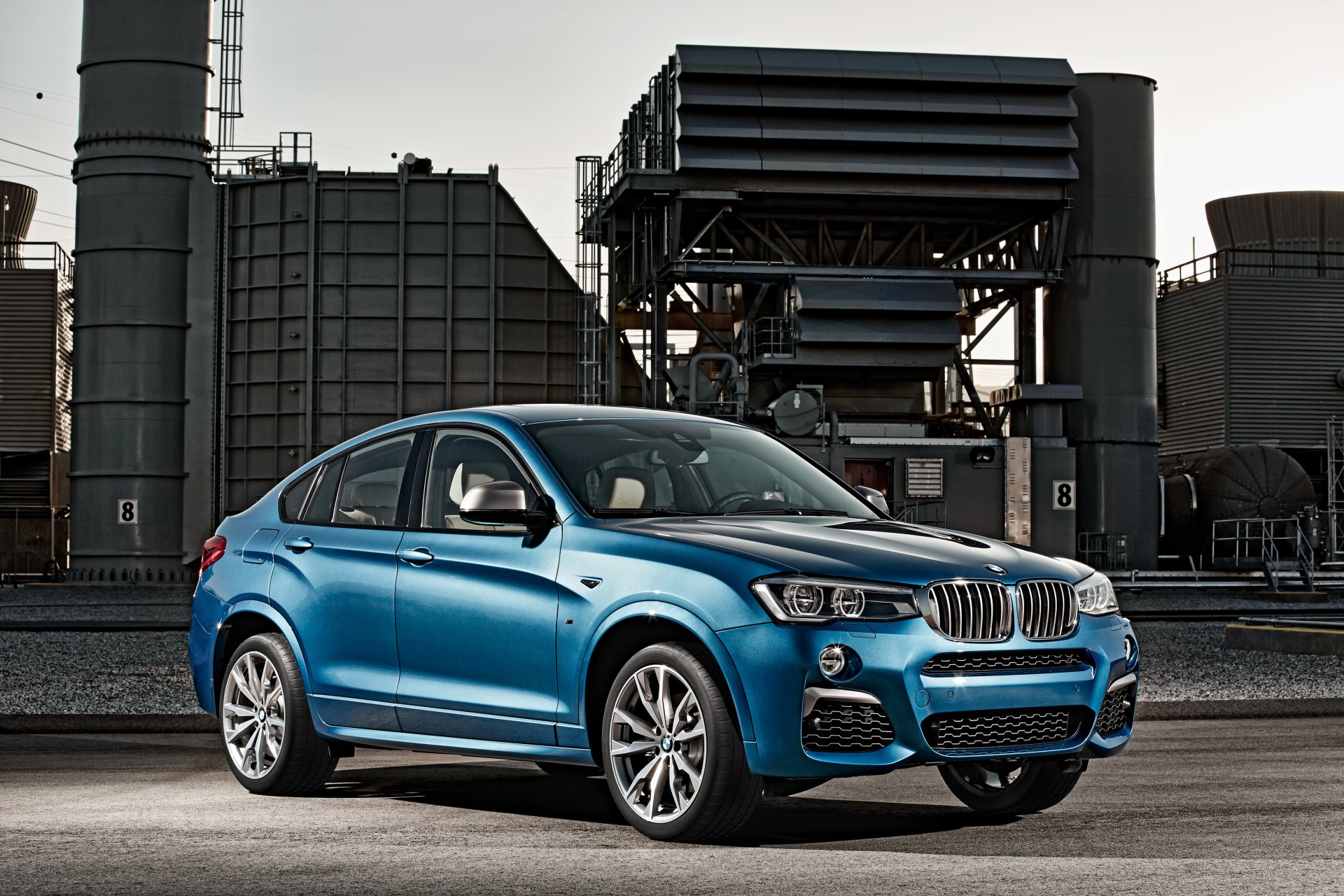 Blue BMW X4 SUV parked before an industrial plant — 4K Ultra HD PC desktop wallpaper/background.