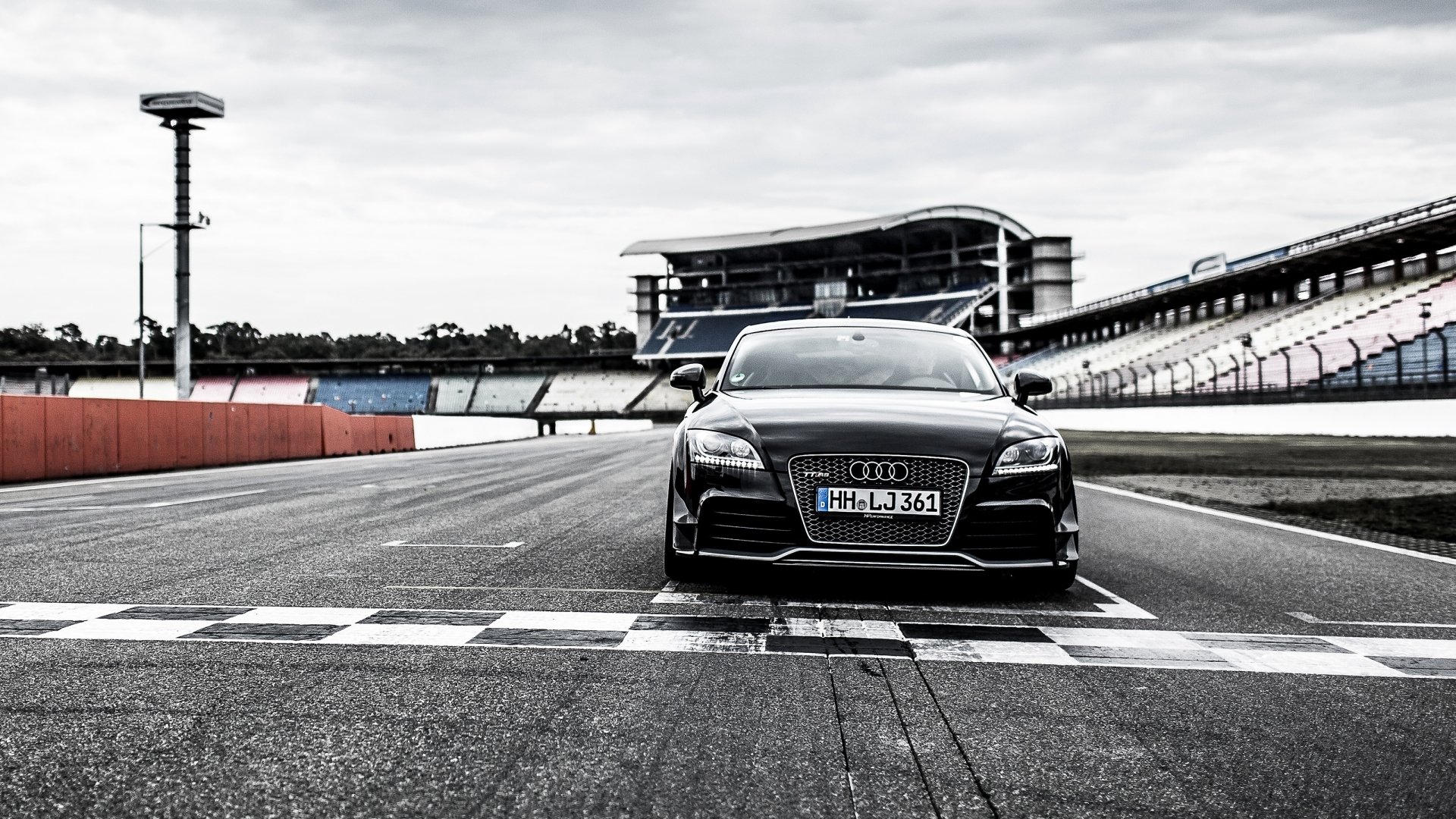 Front view of a black Audi TT sports car on a racetrack starting line, high-contrast 2K Quad HD PC desktop wallpaper/background.