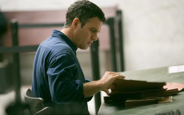 Cinematic still from Spotlight (2015): a man in a blue shirt sorts case files at a desk — 4K Ultra HD PC desktop wallpaper/background.