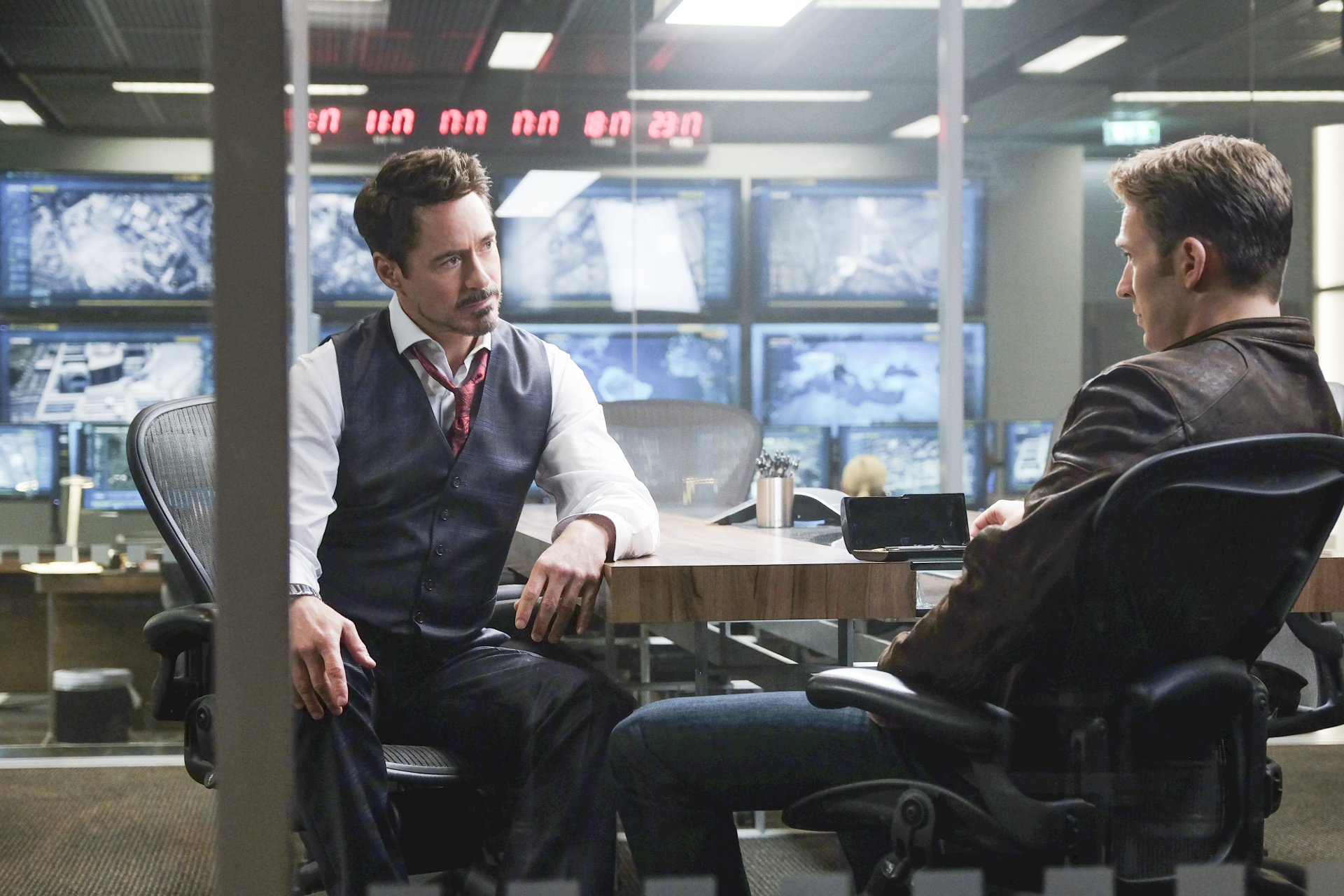Tony Stark and Steve Rogers engage in a tense discussion in a high-tech setting from *Captain America: Civil War*, featuring Robert Downey Jr. and Chris Evans. HD wallpaper.