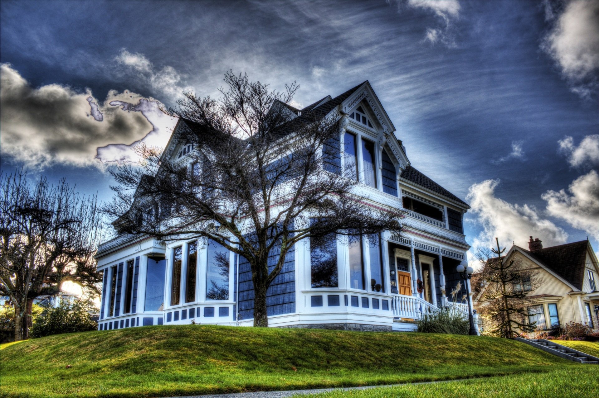 A striking blue Victorian house surrounded by trees under a dramatic sky, featured as an HD PC desktop wallpaper and background.