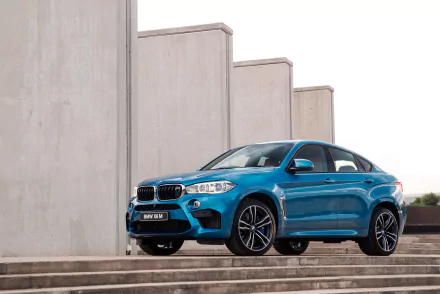 A vibrant blue BMW X6 SUV parked on wide stone steps with modern concrete walls in the background, captured in sharp 4K Ultra HD for a PC desktop wallpaper.