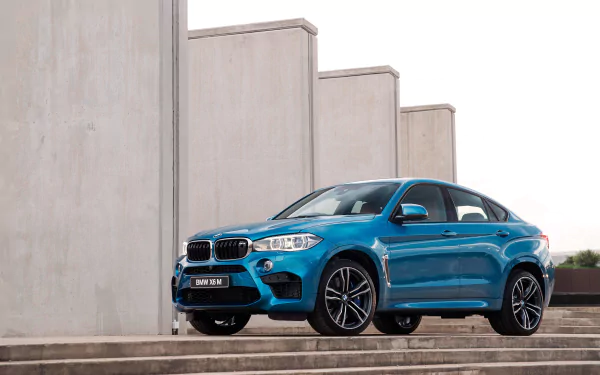 A vibrant blue BMW X6 SUV parked on wide stone steps with modern concrete walls in the background, captured in sharp 4K Ultra HD for a PC desktop wallpaper.