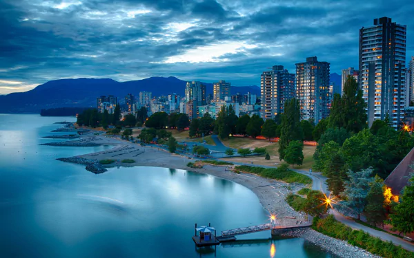 A stunning dusk cityscape of Vancouver, showcasing a serene lake and lush wharf lined with skyscrapers reflecting on the water, creating a captivating urban backdrop.