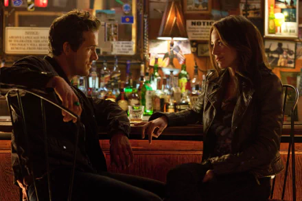 A scene from the movie Green Lantern, featuring Blake Lively as Carol Ferris and Ryan Reynolds as Hal Jordan, deep in conversation in a cozy bar setting. 