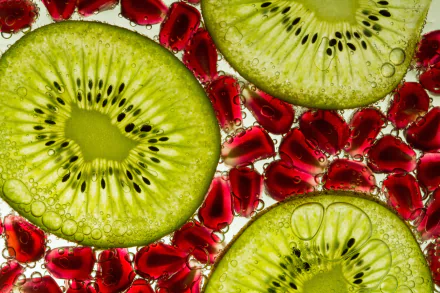 Close-up of vibrant kiwi slices and red pomegranate seeds with water droplets, captured in stunning 4K Ultra HD as a fresh fruit desktop wallpaper background.