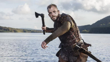 Bearded warrior from the TV show Vikings (2013) on a lakeshore, gripping an axe — cinematic HD PC desktop wallpaper/background.
