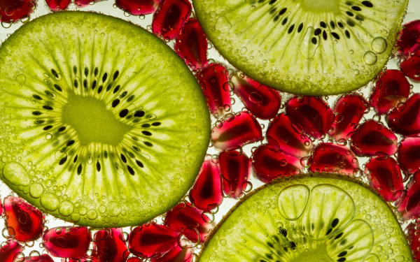 Close-up of vibrant kiwi slices and red pomegranate seeds with water droplets, captured in stunning 4K Ultra HD as a fresh fruit desktop wallpaper background.