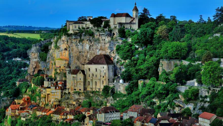 Stone buildings and houses clustered on a cliffside in Rocamadour, France, showcasing a historic man-made cityscape surrounded by greenery.