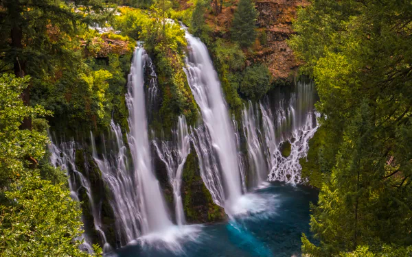 Burney Falls, a California waterfall tumbling over a mossy cliff into a turquoise pool, framed by lush nature — 5K Ultra HD PC desktop wallpaper background.