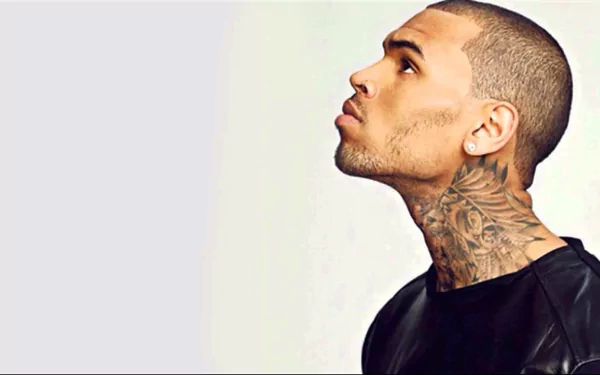 HD PC desktop wallpaper featuring a close-up profile of Chris Brown with visible neck tattoos against a light background, representing music and style.
