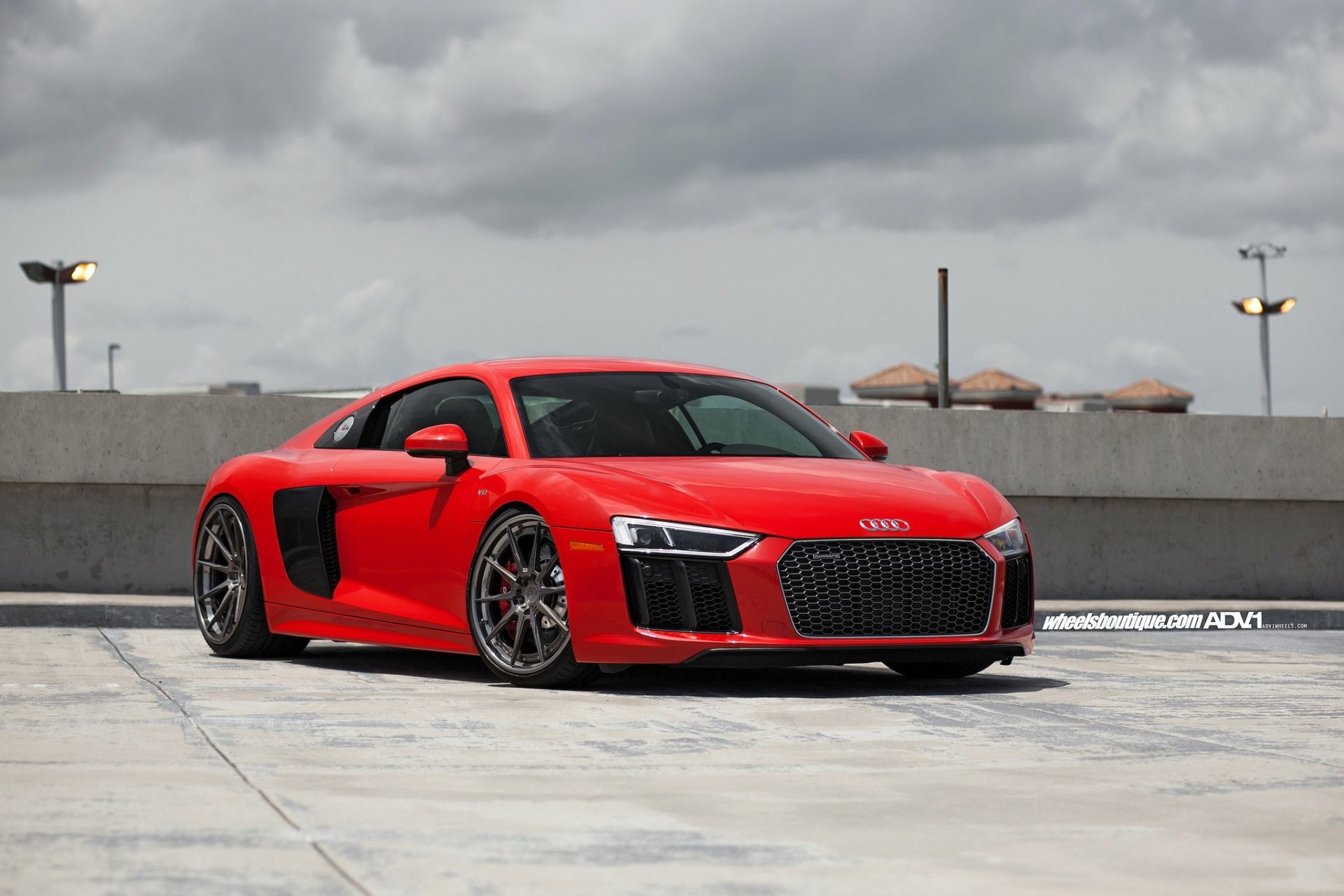 HD desktop wallpaper featuring a red Audi R8 V10 parked on a rooftop against a cloudy sky, showcasing the sleek design of the Audi vehicle.