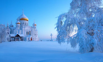 Snow-covered trees frame the Belogorsky Monastery church in winter, Russia, under a clear blue sky in this HD desktop wallpaper and religious landscape.