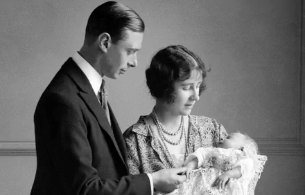 Black and white HD desktop wallpaper featuring a young Queen Elizabeth II with a man, both gazing lovingly at a baby in their arms.