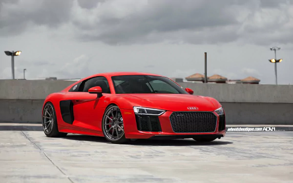 HD desktop wallpaper featuring a red Audi R8 V10 parked on a rooftop against a cloudy sky, showcasing the sleek design of the Audi vehicle.