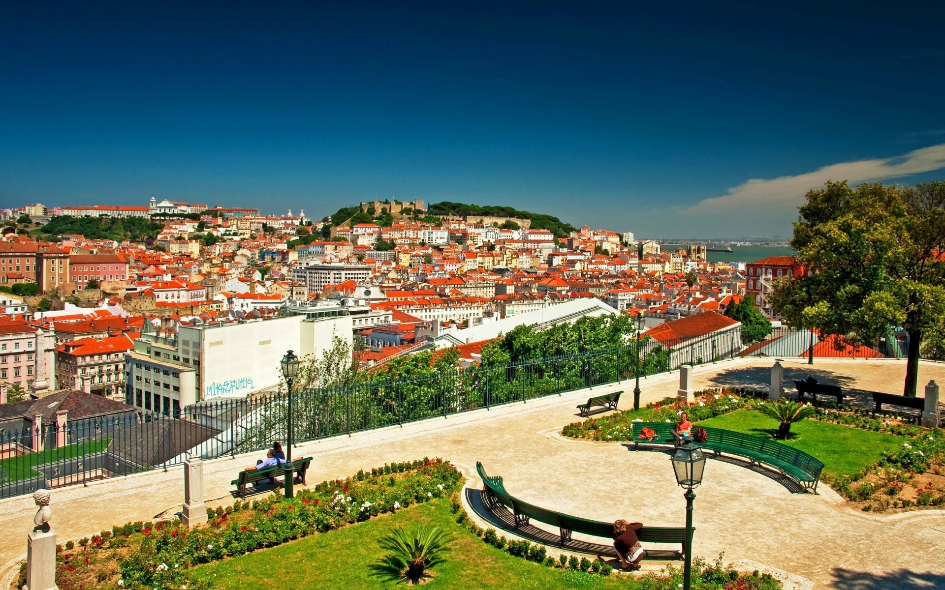 Colorful cityscape of Lisbon, Portugal, showcasing vibrant houses and urban landscape under a clear blue sky, captured as an HD desktop wallpaper.