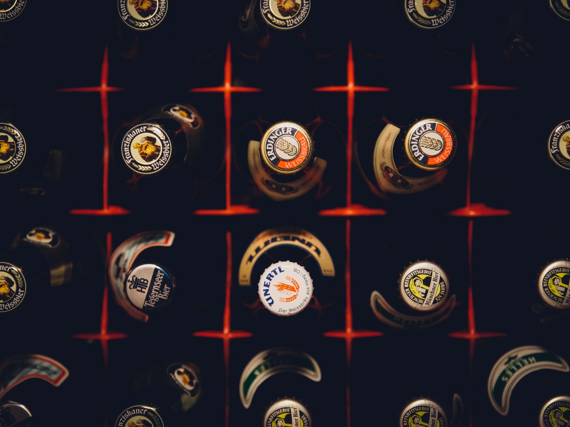 4K Ultra HD wallpaper featuring an artistic overhead view of various beer bottle caps arranged on a dark grid background, highlighting food and beer elements.