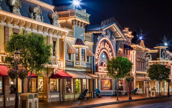 Nighttime view of illuminated Disneyland buildings and stores along a quiet street in the USA, captured in HD for a vibrant desktop wallpaper background.
