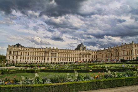4K Ultra HD PC desktop wallpaper: Palace of Versailles façade and formal gardens in Paris under dramatic clouds, man-made terraces, hedges, and reflecting pools.