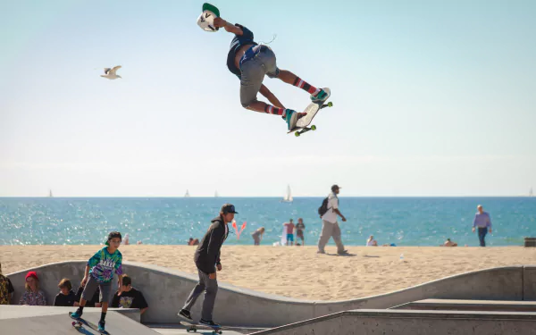 A vibrant urban scene captures skateboarders in motion against a stunning beach backdrop, showcasing the excitement of outdoor sports and skateboarding culture.