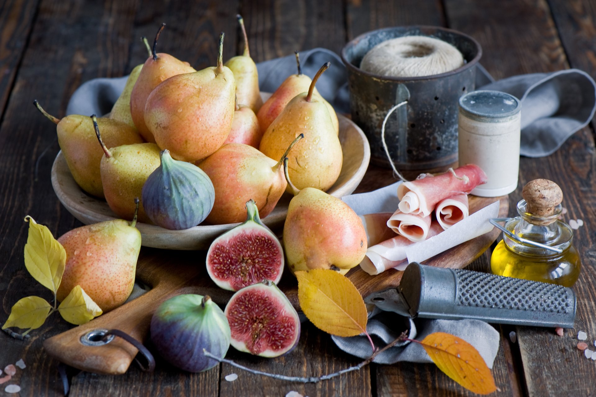 HD still life desktop wallpaper featuring fresh figs and pears arranged on a rustic wooden table with kitchen utensils and autumn leaves.