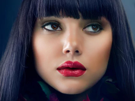 Close-up of a woman with brown eyes and striking red lipstick. This HD image showcases a model's face, highlighting her features and dark hair. A stunning desktop wallpaper.