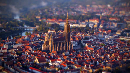 Ulm Minster stands majestically amid a vibrant cityscape in Germany, captured in stunning tilt-shift photography, showcasing intricate architecture and the charm of the surrounding area.
