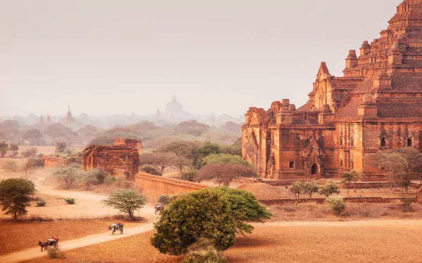 A stunning view of a religious temple monument in Myanmar, showcasing intricate architecture set against a backdrop of serene landscape and dusty pathways.