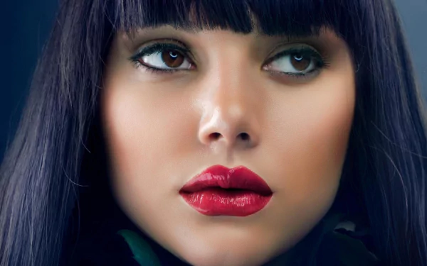 Close-up of a woman with brown eyes and striking red lipstick. This HD image showcases a model's face, highlighting her features and dark hair. A stunning desktop wallpaper.