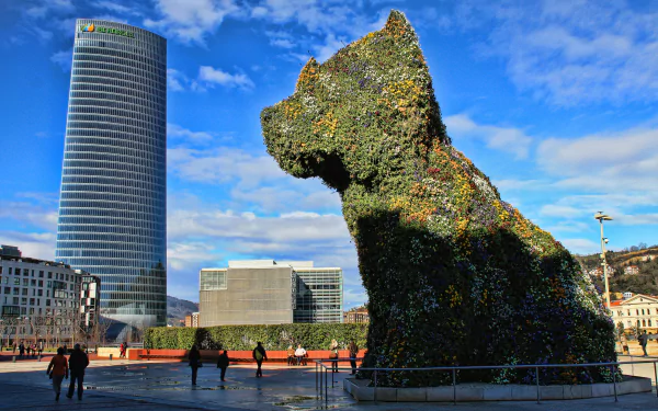 4K Ultra HD PC desktop wallpaper: Bilbao, Spain — Guggenheim Museum's man-made floral Puppy statue beside the Iberdrola Tower under a bright blue sky.