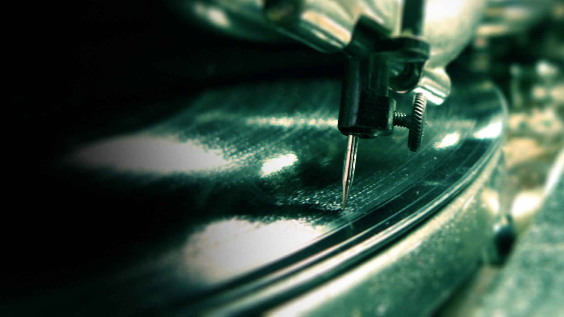 Close-up of a record player's needle on a spinning vinyl record, captured in sharp detail for a HD PC desktop wallpaper background.