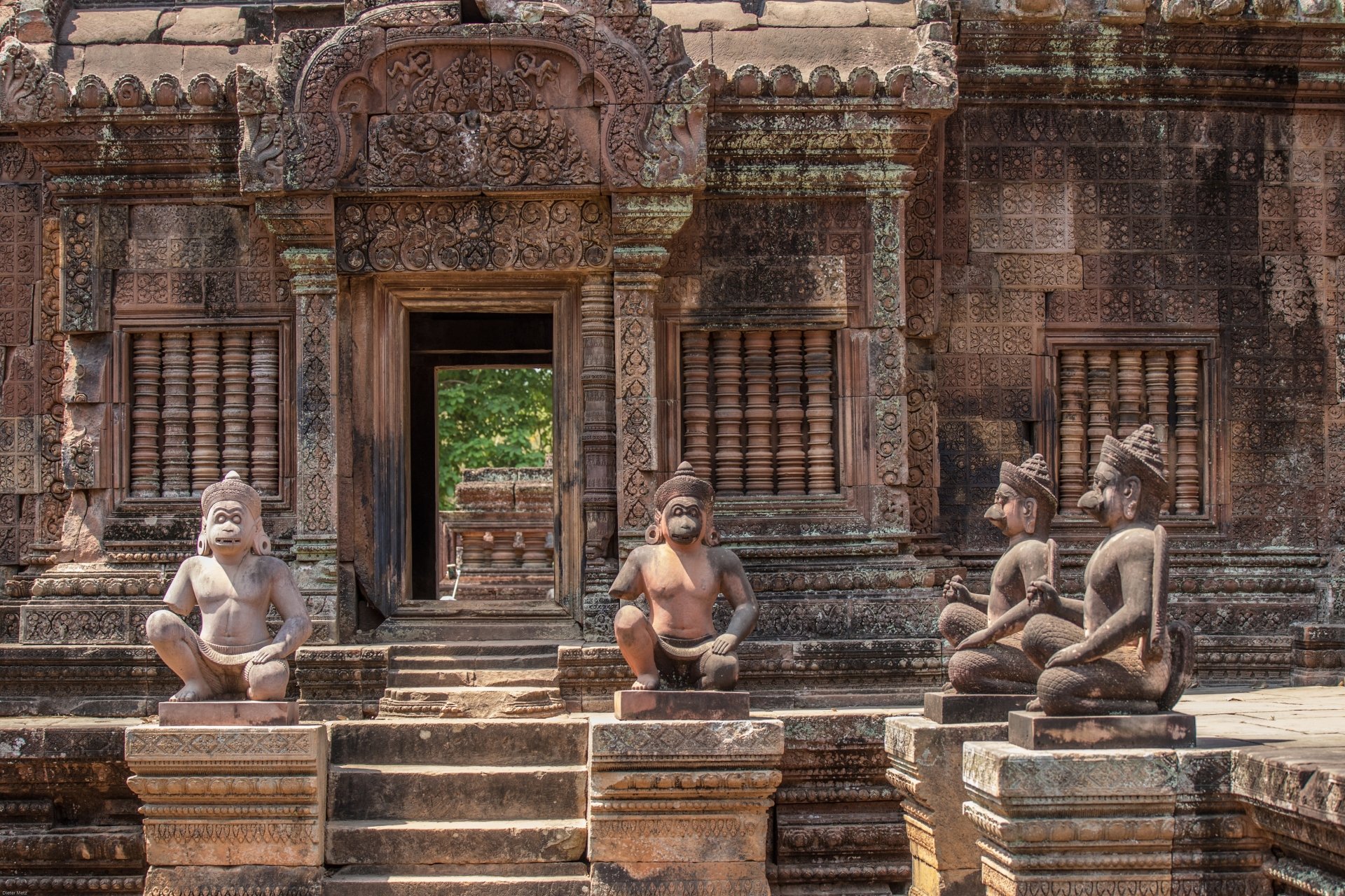 Ancient Hindu statues frame a weathered temple entrance in Angkor Wat, showcasing intricate carvings and the rich history of this religious site. A captivating scene of timeless beauty.