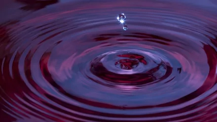 An HD desktop wallpaper featuring a single water drop creating ripples in a pool, set against a serene background with shades of purple and pink.
