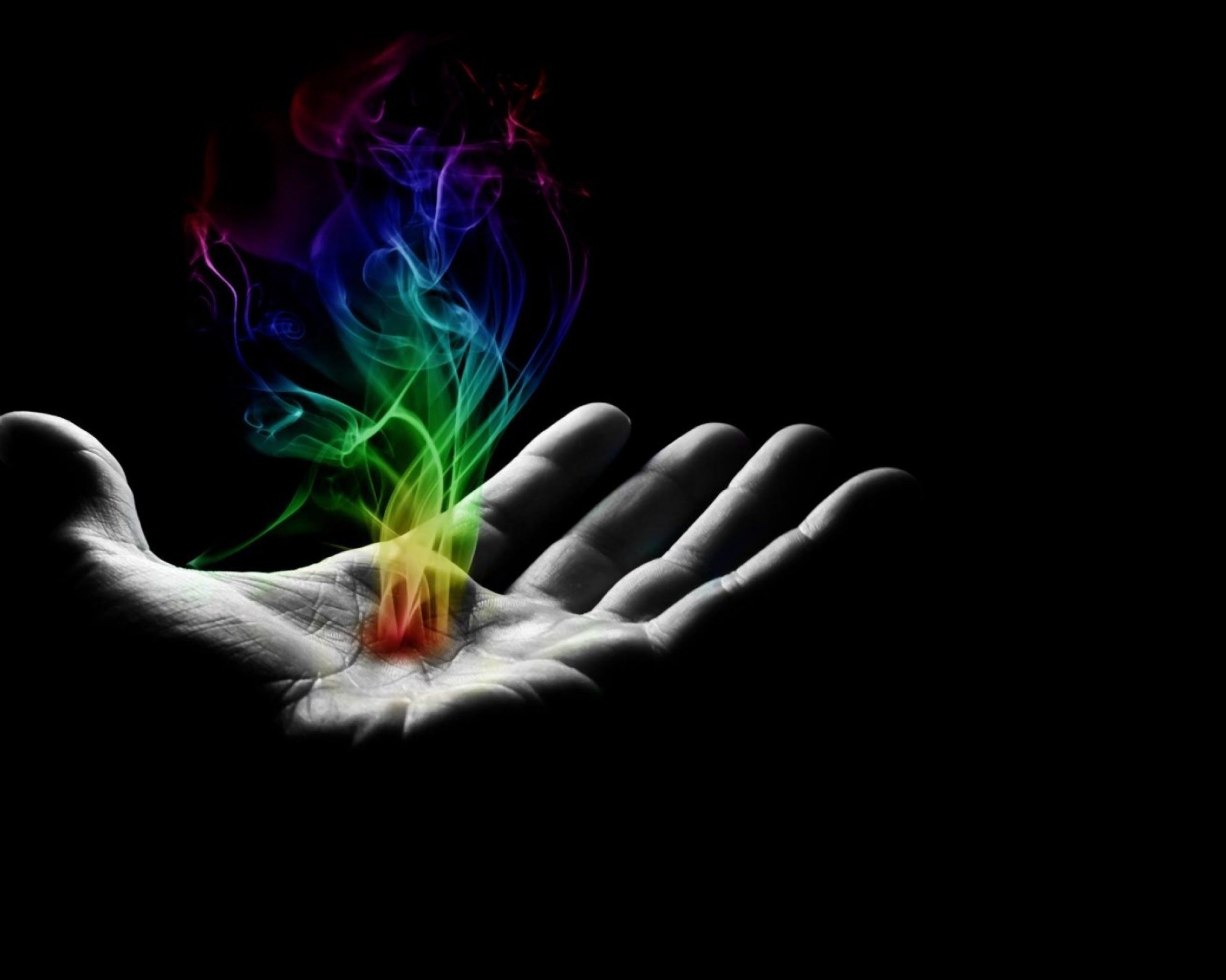 An artistic HD desktop wallpaper featuring a hand illuminated by vibrant, swirling colors against a black background, conveying a sense of creativity and magic.