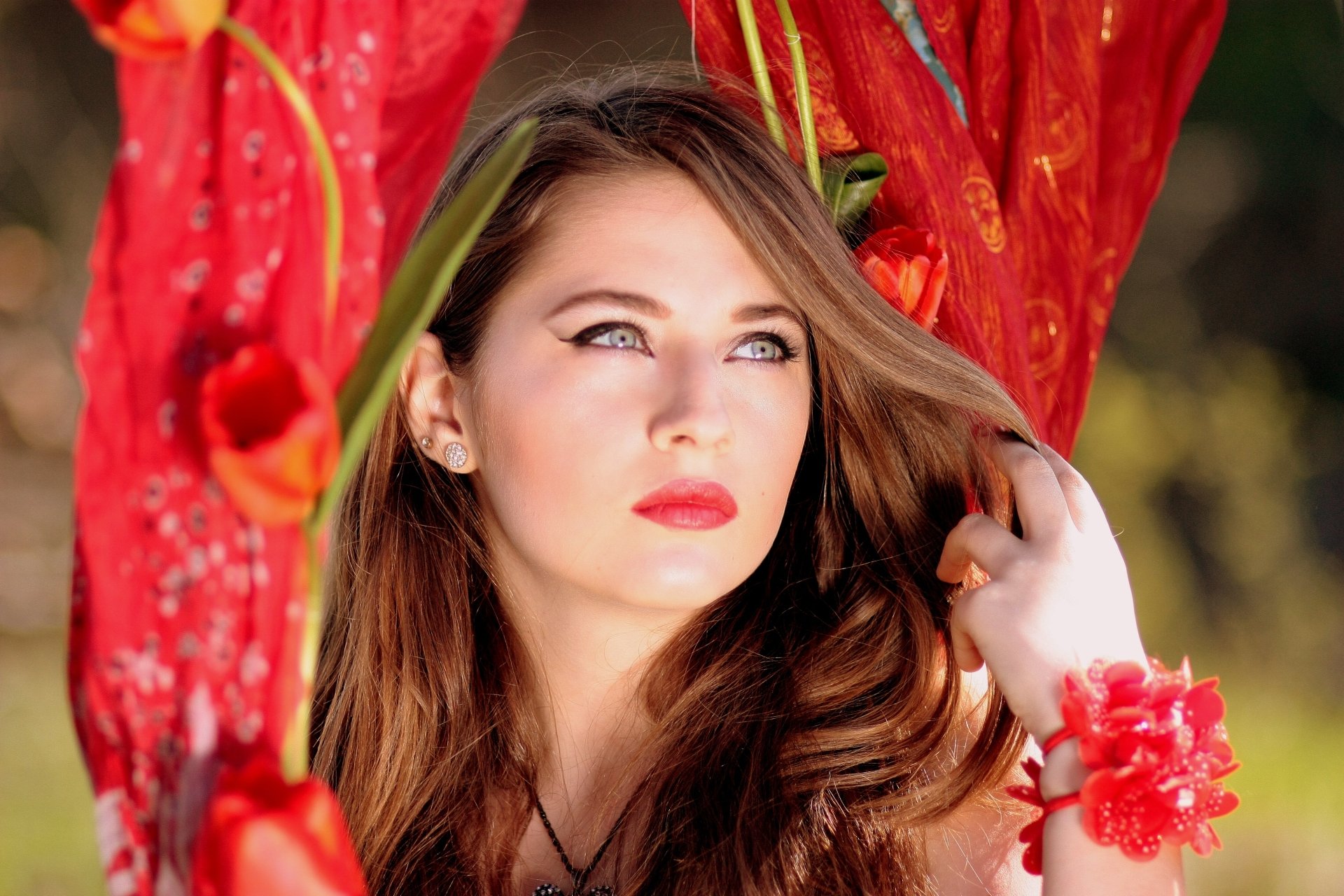 A woman with long hair is posing gracefully, wearing vibrant lipstick and a scarf, surrounded by colorful flowers. This 4K Ultra HD image captures her model-like beauty and elegance.