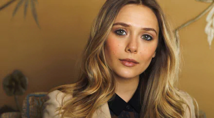 A stunning HD wallpaper featuring celebrity Elizabeth Olsen, showcasing her elegant look with soft waves and a natural makeup palette against a warm, inviting background.