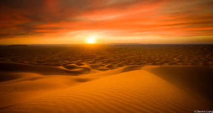 HD PC desktop wallpaper of a desert landscape featuring sand dunes and a vibrant sunset sky on the horizon.