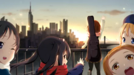 A vibrant HD desktop wallpaper featuring Yui Hirasawa, Tsumugi Kotobuki, Ritsu Tainaka, Azusa Nakano, and Mio Akiyama from K-ON!, against a city skyline at sunset.