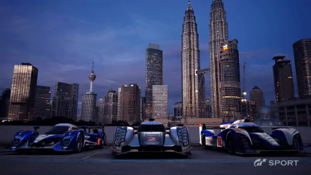HD PC desktop wallpaper featuring sleek race cars parked against the nighttime cityscape of Kuala Lumpur, from the video game Gran Turismo Sport.