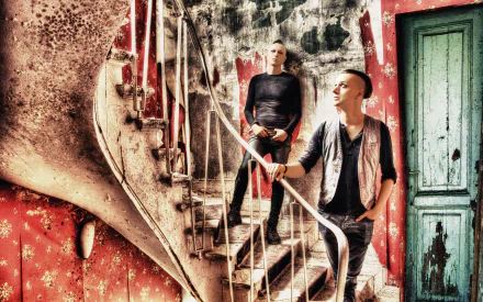 4K Ultra HD desktop wallpaper: two musicians pose on a spiral staircase inside a distressed red interior — promotional music image for Solar Fake.
