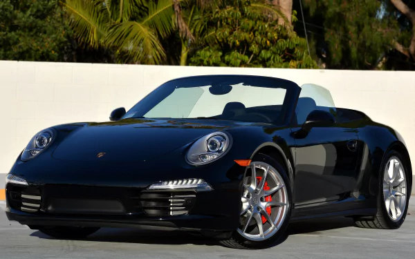 Black Porsche 911 Carrera 4S convertible parked by a white wall with palm trees — 4K Ultra HD PC desktop wallpaper.