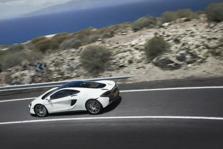 White McLaren 570GT supercar driving on a coastal road, 4K Ultra HD PC desktop wallpaper background.