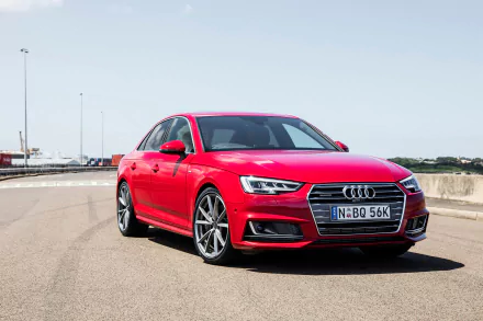 A striking red Audi A4 parked on a scenic road, showcasing its sleek design and modern features. This high-definition image serves as an impressive desktop wallpaper.