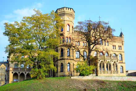 A beautiful palace surrounded by lush trees in Lithuania, showcasing stunning architecture against a clear blue sky. An enchanting blend of nature and man-made design.