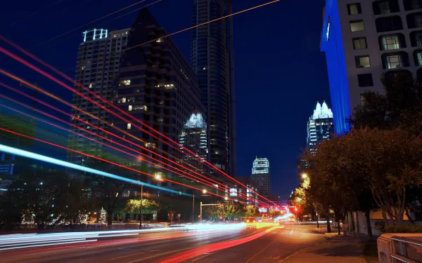 Time-lapse night view of Austin, Texas cityscape featuring illuminated skyscrapers and streaks of light from moving vehicles.