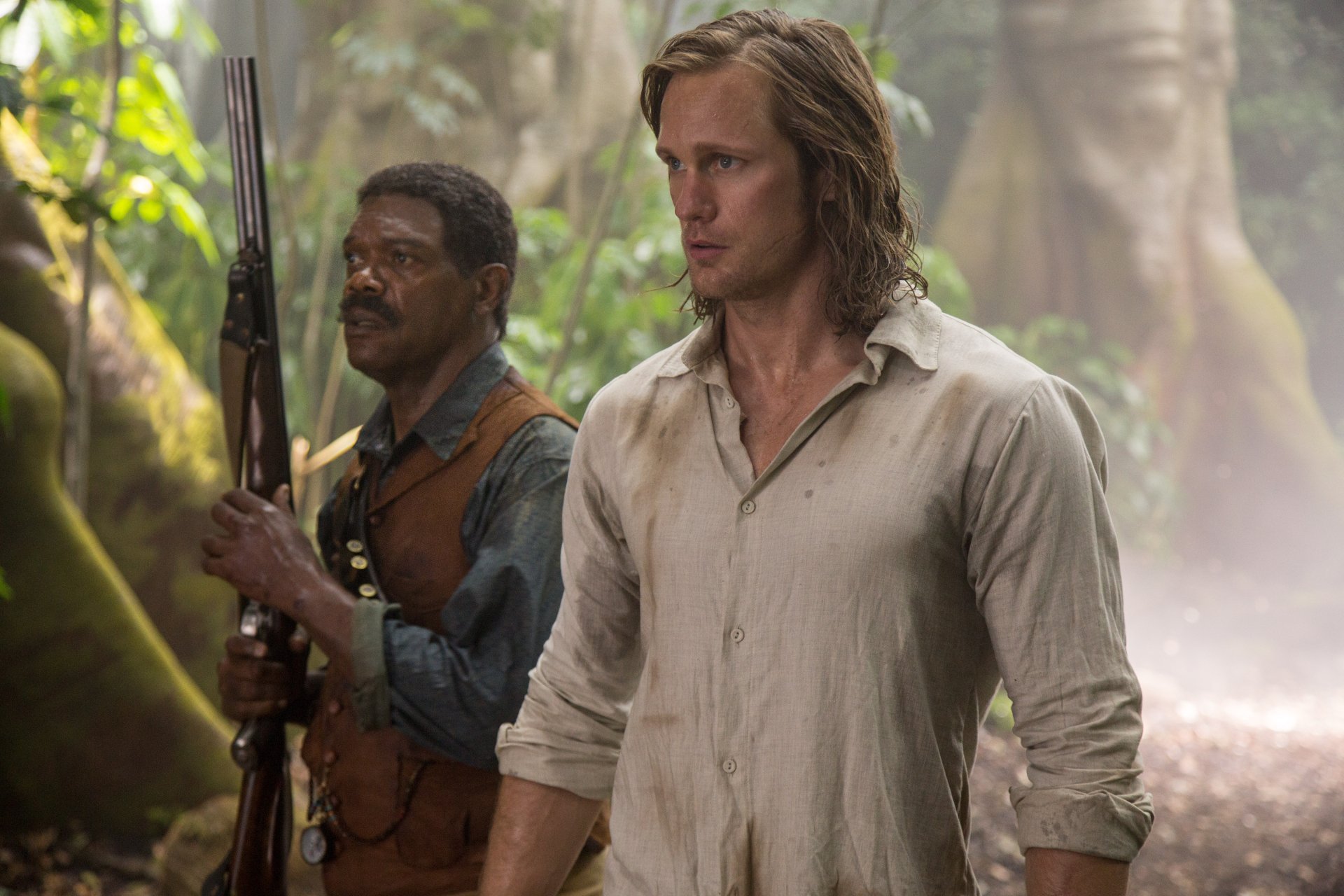 5K Ultra HD PC desktop wallpaper: two actors from The Legend of Tarzan in a misty jungle — a rifle-bearing man in a vest and a long-haired man in a light open shirt.